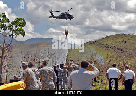 Les aviateurs de l'armée de la Garde nationale de Porto Rico dans un UH-60 Black Hawk helicopter drop 550 gallons d'eau d'un seau Bambi sur un feu lors d'une mission de formation il Camp Santiago Centre mixte, Salinas, Puerto Rico. La formation combine des éléments du PRNG et PRFD afin de mieux se préparer pour le reste de la saison à venir. (U.S. Photo de l'armée par le sergent. Joseph Rivera Rebolledo, spécialiste des affaires publiques, Puerto Rico) pompiers militaires de la Garde nationale de former avec les Pompiers Pompiers 130501-A-SM948-767 Banque D'Images