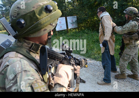 Un soldat de l'armée géorgienne de Delta Entreprise, 31e Bataillon d'infanterie légère d'une recherche nationale locale, reproduite par un rôle civil dvd, tandis qu'un autre soldat tire la sécurité pendant un exercice de répétition de mission (MRE) au Centre de préparation interarmées multinationale (JMRC) dans Hohenfels, Allemagne, 14 août 2013. L'Batoumi et 31e bataillons d'infanterie légère géorgienne conduite un MRE afin de former et d'être évalués sur les bataillons leur aptitude à mener des opérations de contre-insurrection et de combat et s'intégrer dans une équipe de combat du régiment du Corps des Marines déployées à l'appui de l'aide de la sécurité internationale Banque D'Images