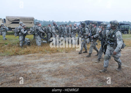 48e Brigade d'infanterie, XCTC GARRSON GÉORGIE TRAINING CENTRE, Fort Stewart, le 22 septembre 2013, Ga, Géorgie - Garde nationale d'armée le s.. Nicholas Jelks, un chef d'équipe avec la Compagnie Charlie, 1er Bataillon, 121st, de l'infanterie (à droite), promenades avec les membres de son équipe de craie que le reste de la Compagnie Charlie, dans l'arrière-plan, préparez-vous à bord d'un convoi de camions 13 qui va les prendre leur prochaine destination où ils vont sur l'agression d'un objectif au cours de l'Entraînement au Combat exportables (XCTC) entraînement à Fort Stewart. Jelks est un Atlanta, Géorgie, native. Il travaille à temps plein avec la Georgia National Banque D'Images