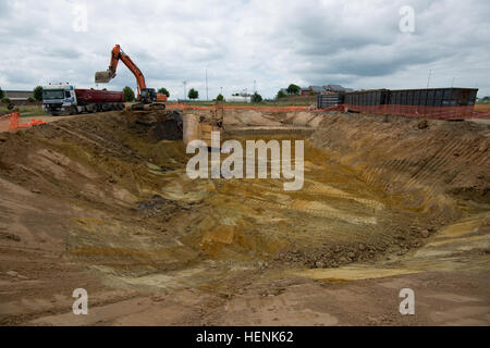 Un excavateur à chenilles exploitées par des entrepreneurs belges creuse les zones entourant un ancien site de stockage de carburant jet sur la base aérienne de Chièvres pour retirer, test, et si nécessaire, décontaminer le sol à Chièvres, Belgique, le 20 juin 2014. Le travail est coordonné entre les corps des ingénieurs, la Division de l'environnement, Ministère des Travaux publics, de la garnison de l'armée des États-Unis et le Benelux, Ministère belge de la Défense. (U.S. Photo de l'armée de l'information visuelle) Courtejoie-Released Pierre-Etienne Spécialiste décontamination POL USAG Benelux 140620-A-BD610-007 Banque D'Images