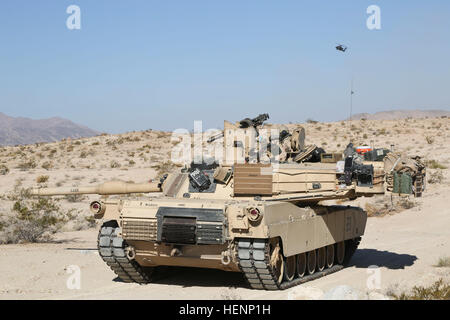 D'un M1 Abrams tank grâce à des manœuvres au Centre national de formation tandis qu'un hélicoptère AH-64 Apache fournit un appui aérien aux soldats de l'armée américaine de la Compagnie Alpha, 3e Bataillon, 69e régiment de blindés, 1st Armored Brigade Combat Team, 3e Division d'infanterie, au cours d'une action décisive 14-09 Rotation à Fort Irwin, en Californie, 9 août, 2014. L'action décisive de l'environnement de formation ont été développés pour les rotations créer un scénario de formation commune pour l'ensemble de l'armée. (U.S. Photo de l'armée par la CPS. Randis Monroe/libéré) Abrams manoeuvre 140809-A-XB890-015 Banque D'Images