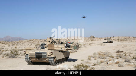 D'un M1 Abrams tank grâce à des manœuvres au Centre national de formation tandis qu'un hélicoptère AH-64 Apache fournit un appui aérien aux soldats de l'armée américaine de la Compagnie Alpha, 3e Bataillon, 69e régiment de blindés, 1st Armored Brigade Combat Team, 3e Division d'infanterie, au cours d'une action décisive 14-09 Rotation à Fort Irwin, en Californie, 9 août, 2014. L'action décisive de l'environnement de formation ont été développés pour les rotations créer un scénario de formation commune pour l'ensemble de l'armée. (U.S. Photo de l'armée par la CPS. Randis Monroe/libéré) Abrams manoeuvre 140809-A-XB890-017 Banque D'Images