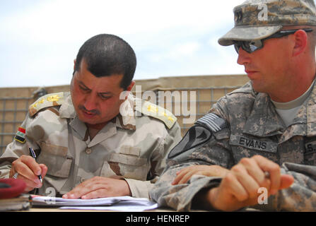 Le Capitaine Daniel Evans regarde sur comme un chef de l'armée irakienne avec la 2e Brigade, 1ère Division de l'armée iraquienne les signes d'une force de réaction rapide pour le Camp Tariq, l'Iraq, le 12 mai 2011. Evans, commandant de la Compagnie C, 3e Bataillon, 15e Régiment d'infanterie, et environ 80 de ses soldats s'installe à Fallujah Camp après avoir tourné plus de Tariq pour le ministère irakien de la Défense. (U.S. Photo de l'armée par le sergent. Tanya Thomas, 4e Aab, 3ème Inf. Div., USD-C) plusieurs bases fermer en Iraq en tant que 4ème AAB, 3ème Inf. Div. commence trek home 110512-A-EC832-089 Banque D'Images