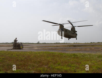 Le Sgt. Anton Novosselov et la FPC. Nathan Watson avec 372e de transfert de cargaison à l'intérieur des terres, de l'entreprise 129e Bataillon de soutien au maintien en puissance de combat, la 101e Brigade de soutien, Groupe de travail Lifeliner, à partir de Fort Campbell, Ky., attendre un hélicoptère Chinook Cargo (47) de les approcher à charge un ensemble de carburant d'urgence à un laboratoire médical mobile à Greenville, Libéria, dans le cadre de l'opération Assistance aux 21 décembre, 2014. Le 2e Bataillon de l'aviation d'appui général, 501e Régiment d'aviation, 1st Armored Division Aviation Brigade, de Fort Bliss, Texas, à condition que l'appui de l'aviation, Aérodrome Roberts Monrovia Banque D'Images