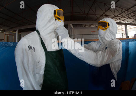 Deux travailleurs de la santé vérifier l'équipement de protection personnelle durant leur évaluation finale à l'intérieur d'une simulation d'unité de traitement de l'Ebola dans le cadre du ministère de la défense de l'équipe de formation Traitement d'Ebola dernière classe à l'École de police nationale, Paynesville, Libéria, 23 décembre 2014. Le DET-3 est prévue pour faire une transition cruciale de sa mission retour à l'Organisation mondiale de la santé, l'ETU des travailleurs de la santé qui ont été formés comme formateurs, et PAE, une entreprise contractante, le 1 er janvier 2015. L'OMS, qui a créé le cours en collaboration avec le ministère de la Santé, a b Banque D'Images