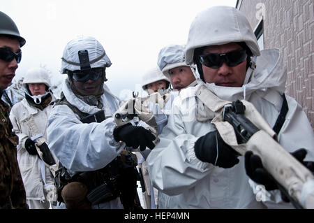 Le Sgt. Emmett Browne (à gauche), chef d'équipe à la U.S. Army Alaska's 1er Bataillon (Airborne), 501e Régiment d'infanterie, d'infanterie 4e Brigade Combat Team (Airborne), 25e Division d'infanterie, des trains avec des soldats japonais du 27e Régiment d'infanterie, 5e Brigade, Armée du Nord, le Japon d'autodéfense au sol pendant les opérations militaires en milieu urbain dans le cadre de l'exercice 2015 Yausubetsu Vent du nord au domaine de formation, Hokkaido, Japon, le 12 février 2015. La brigade de parachutistes avec Spartan sont au Japon pour participer à l'exercice du vent du nord 2015, deux semaines de formation sur le terrain et bilatérales post-commande exe Banque D'Images