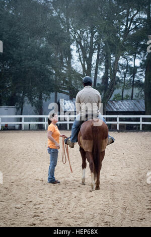 Un membre de la base aérienne d'Eglin, du sable et de stimuler l'Riding Club, gauche, enseigne un soldat des Forces spéciales affecté à la 7e Special Forces Group (Airborne) comment bien monter un cheval le 5 mars. Les membres de l'riding club heled de bérets verts à partir de l'unité d'apprendre à bien prendre soin de, d'emballage et monter des chevaux, l'amélioration de leurs moyens d'infiltration et d'accroître leur mobilité pendant le déploiement de lieux rudimentaires. Bérets verts Apprendre l'équitation 150305-A-KJ310-006 Banque D'Images