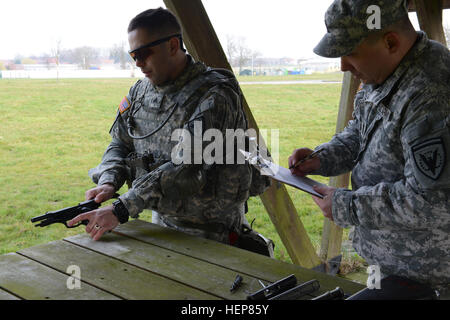 Le sergent de l'armée américaine. Joe Primeau affectés à des Forces alliées Nord bataillon, se compose d'un pistolet M9 en vertu de l'inspection du 1er Sgt. Richard Williams (États-Unis Forme de commandement européen de l'enquête) au cours de l'exercice d'entraînement de brigade (STX) à l'Alliance d'entraînement (ATA), dans la base aérienne de Chièvres, Belgique, le 24 mars 2015. (U.S. Photo de l'armée par Visual Spécialiste de l'information Pascal Demeuldre-Released) MILLIARDS D'AFNORTH exercice d'entraînement de brigade (STX) 150324-A-RX599-035 Banque D'Images