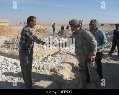 Mustasher Fahad Saleh salue 1st. Le Lieutenant Dale Cox, un chef de section de Columbus, Ohio, sur le chantier de l'école Al Salman en Iraq's province Muthanna. Cox est déployée au sud de l'Iraq avec 4e Brigade, 1e Division blindée de l'Armée de 'premier conseiller et aider' brigade. Investir dans la prochaine génération de l'Iraq 229233 Banque D'Images