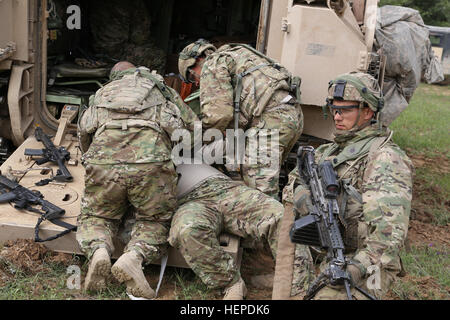 Les soldats américains du 10e bataillon du génie de la Brigade, 1e Brigade Combat Team, 3e Division d'infanterie, effectuer de l'aide médicale alors qu'un autre soldat de sécurité arrière fournit le cadre de l'exercice Combined Résoudre IV à l'armée américaine dans le centre de préparation interarmées multinationale Hohenfels, Allemagne, le 25 mai 2015. Résoudre combiné IV est une armée Europe réalisé l'entraînement à l'exercice une brigade multinationale et renforcer l'interopérabilité avec les alliés et les pays partenaires. Les trains combinés résoudre sur terre unifiée des opérations contre une menace complexe tout en améliorant la préparation au combat de tous les participants. La résoudre Banque D'Images