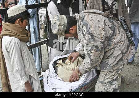 Un agent de police de patrouille à la frontière afghane regarde à travers un sac dans une brouette du garçon sur la passerelle piétonne le 7 mars à Torkham Gate sur la frontière de l'Afghanistan et du Pakistan. Red Bulls aident à protéger les soldats de la frontière de l'Afghanistan 376183 Banque D'Images