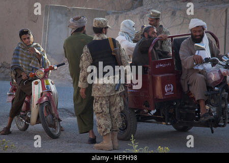 Un Afghan National Civil Order Police recherche un homme sur une moto à un point de contrôle tactique lors d'une mission menée par des soldats de l'Armée américaine affecté à la Compagnie Alpha, 5e Escadron, 1e régiment de cavalerie, 25e Division d'infanterie, pour patrouiller les rues en dehors des combats post exploitation 8-1, au centre-ville de la ville de Kandahar, Afghanistan, le 30 mai. L'objectif de la mission est de mettre en place des points de contrôle tactique pour fouiller les véhicules/occupants, et pour recueillir de l'ambiance de l'ensemble de la population. L'opération Enduring Freedom-Kandahar Ville 110530-A-U825-010 Banque D'Images