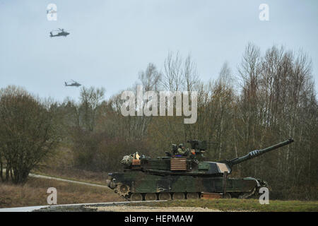 Les soldats du 1er Bataillon, 64e régiment de blindés, 1st Armored Brigade Combat Team, 3e Division d'infanterie, regarder vers le bas dans un M1A2 Abrams Sepv2 char de combat principal comme AH-64 Apaches passez au-dessus lors d'un bras combiné exercice de tir réel à la commande multinational interarmées dans Grafenwoehr, Allemagne, 19 novembre 2015. L'exercice a été l'occasion de l'événement culminant pour résoudre combiné V, une Europe de l'armée américaine-dirigé un exercice multinational avec plus de 4 600 participants de 13 pays de l'OTAN et des pays partenaires européens. Résoudre combiné V est conçu pour exercer l'Armée américaine à l'échelle régionale à force alignés Banque D'Images