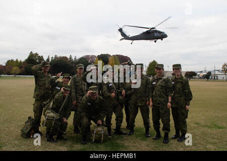 Le Japon d'Autodéfense de masse (JGSDF) réserve de candidats le 117e Bataillon, formation, accrochez JGSDF à leur tête comme un UH-60 Black Hawk de l'Armée américaine du Japon (USARJ) Aviation Battalion descend pour un atterrissage à l'Sagami Depot, Japon, 19 novembre 2015. Plus tôt ce jour-là, les candidats se sont envolés de la 117e bataillon de la formation au Camp Takeyama, Japon, a participé à une série d'événements qui a abouti à un engagement bilatéral mené par l'Engagement de l'Armée de terre Team-Japan (ARET-J). L'ARET-J paniers la journée avec des présentations, à pied Banque D'Images