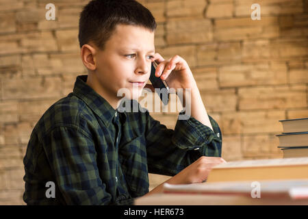 Young Boy Talking on Cell Phone at home. Parler de téléphone mobile Concept. Banque D'Images