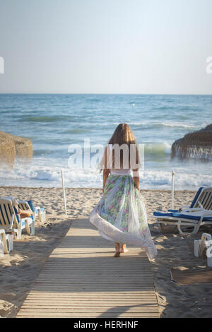 Jeune femme marchant le long trottoir de bois vers la plage Banque D'Images