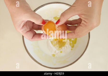 Fissuration femme un oeuf dans bol de farine Banque D'Images