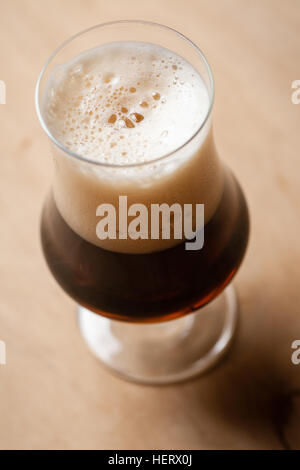 Verre tulipe pleine de bière stout foncé sur une table en bois texturé Banque D'Images