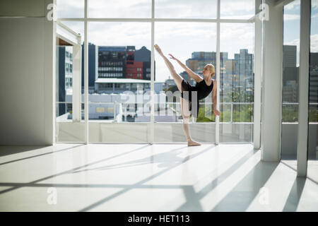 Ballerine qui s'étend sur un mur tout en pratiquant la danse de ballet dans le studio Banque D'Images