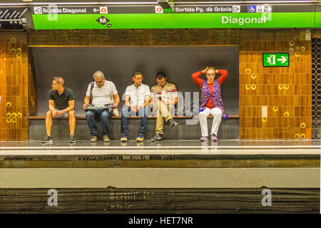 Des gens assis sur un banc en attendant le métro à la station de métro Diagonal, Barcelone, Espagne. Banque D'Images