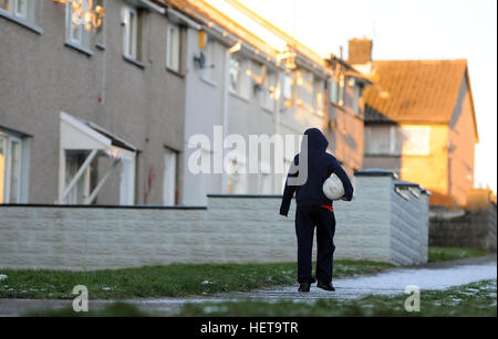 Un garçon marche sur un chemin couvert de neige sur le Gurnos logement Conseil estate dans Merthyr Tydfil, South Wales, UK. Banque D'Images