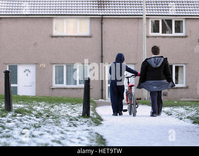 Deux jeunes garçons à pied sur un chemin couvert de neige sur le Gurnos housing Council estate dans Merthyr Tydfil, South Wales, UK. Banque D'Images