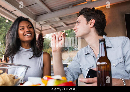 Jeune couple assis sur la véranda, enjoying meal Banque D'Images