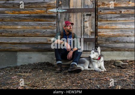 Man with dog reposant par cabane en bois, Walton lake, Oregon, USA Banque D'Images