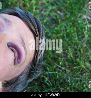 Portrait de l'homme avec des yeux noirs lying on grass Banque D'Images