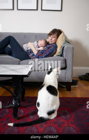 Mère et bébé garçon couché sur le canapé à la recherche à cat Banque D'Images