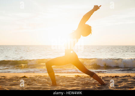 Woman on beach flexion bras levés vers l'arrière faisant l'exercice d'étirement Banque D'Images