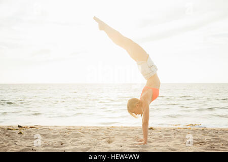 Woman on beach doing handstand Banque D'Images