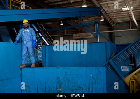 Portrait of male worker in hard hat standing sur bleu de la machinerie lourde à l'usine de recyclage Banque D'Images