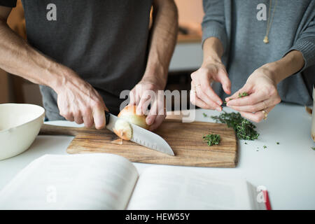 Mid section of couple hacher des oignons dans la cuisine Banque D'Images