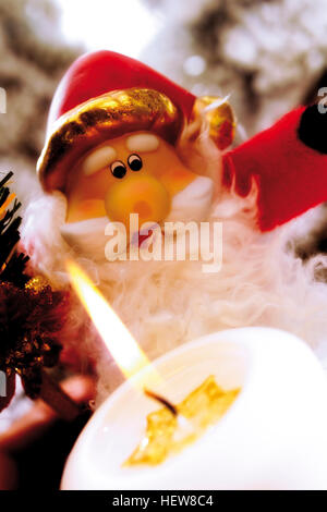 Brûler bougie blanche en face d'un Père Noël Décoration figurine Banque D'Images