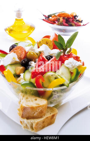 Salade grecque dans un bol en verre avec fromage feta, tomates, cornichons, piments, et olives vertes et noires et servi avec Banque D'Images
