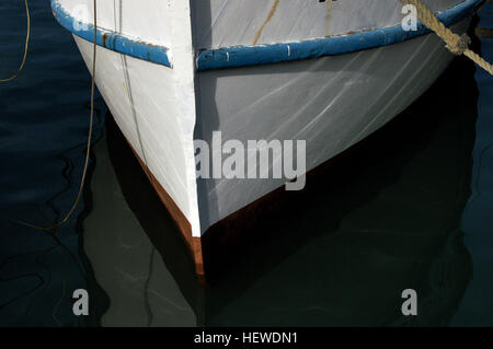 Cette image montre un bateau de pêche blanc et bleu avec sa coque et sa proue mises en évidence. La photo capture l'extrémité avant du bateau amarré à une marina, illustrant les caractéristiques du bateau dans un cadre maritime. Banque D'Images