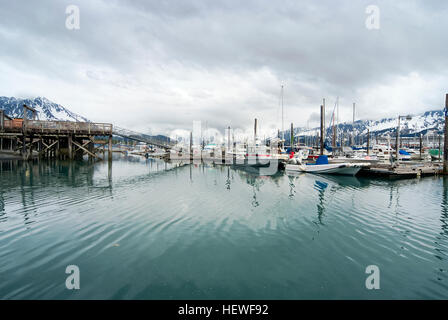 Vue sur les bateaux de pêche amarrés au port de Seward et montagnes couvertes de neige derrière, Alaska Banque D'Images