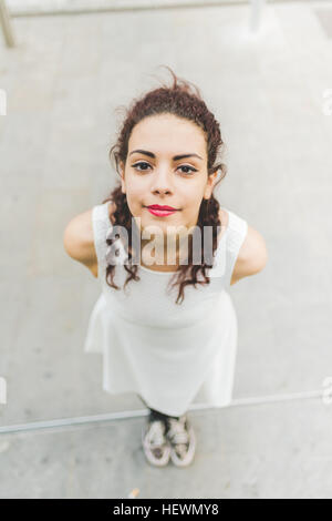 High angle portrait de femme, les mains derrière retour looking at camera Banque D'Images