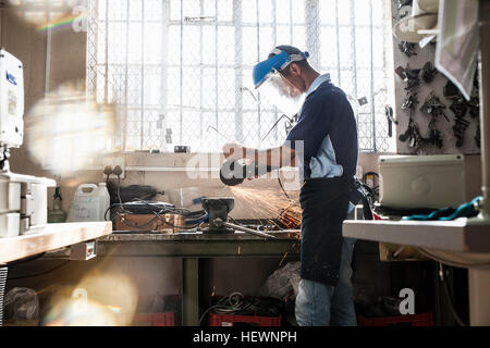 Jeune homme à l'aide d'angle meuleuse à vice en atelier de réparation Banque D'Images