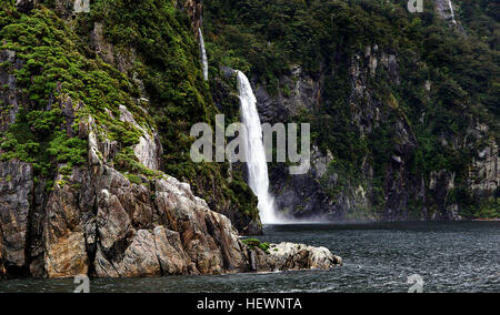 Ou bien humide, Milford Sound est incroyablement grand. Mitre Peak magnétise les photographes, et les falaises du fjord excite tant d'admiration et d'appréhension. Milford Sound est de loin le plus connu de tous les fjords et le seul qui peut être accessible par la route. Il est à environ 16km à partir de la tête du fjörd à la mer ouverte, ce qui signifie que les visiteurs peuvent facilement parcourir la longueur du fiord de la haute mer et de retour sur l'une des nombreuses options de croisière disponibles en 1½ à 2 heures Temps de croisière. Banque D'Images