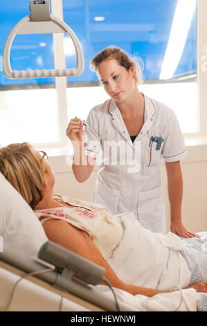 Nurse tending to patient in hospital bed Banque D'Images