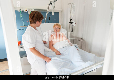 Nurse tending to patient in hospital bed Banque D'Images