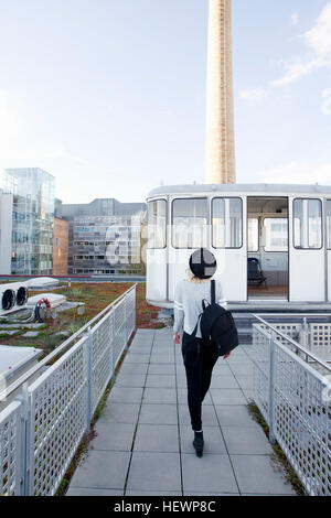 Rear view of woman wearing hat exerçant son sac à dos sur le toit-terrasse Banque D'Images