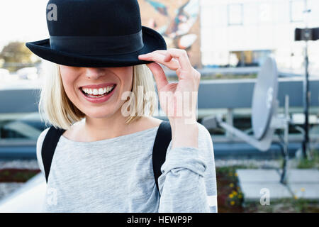Portrait of blond haired woman wearing hat smiling over eyes Banque D'Images
