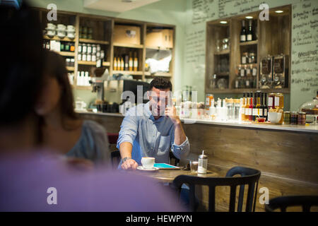 Man sitting in cafe parler sur smartphone Banque D'Images