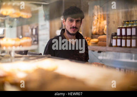 Portrait de jeune homme derrière barista cafe counter Banque D'Images