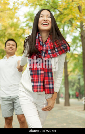 Jeune femme tirant petit ami par la main dans la région de autumn park, Beijing, Chine Banque D'Images