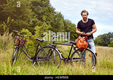 Cycliste masculin déballage holdall in rural field Banque D'Images