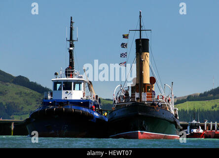 L'image montre un bateau à vapeur amarré à Port Lyttleton, en Nouvelle-Zélande, avec des remorqueurs aidant dans le port. Port Lyttleton est un port important pour Christchurch, jouant un rôle important dans le commerce maritime et la logistique. Banque D'Images